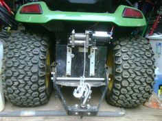 the rear end of a green four - wheeler with large tires and yellow rims