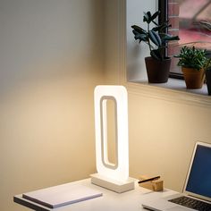 a laptop computer sitting on top of a desk next to a light that is shaped like an o