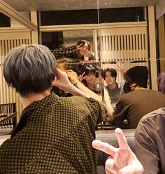 a group of people sitting in front of a mirror with their hands up to the side