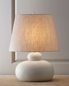 a white table lamp sitting on top of a wooden table