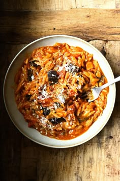 a bowl of pasta with olives and parmesan cheese