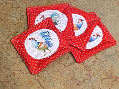 four red coasters with rooster designs on them