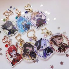 six anime keychains are shown on a white surface with stars in the background