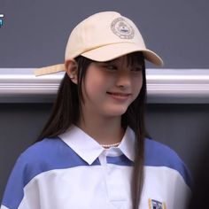 a girl with long hair wearing a white and blue shirt, hat and baseball cap