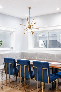 a dining room table with blue chairs and a chandelier