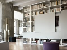 a living room filled with lots of white furniture and bookshelves next to a window