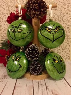 some green ornaments with faces on them and pine cones