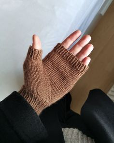 a person's hand wearing a brown knitted mitt sitting on top of a couch