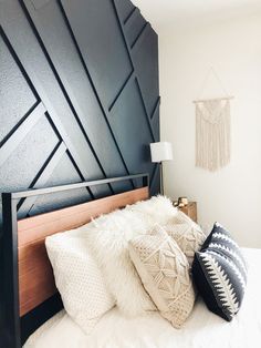 a bedroom with black and white decor on the wall, bedding and pillows in front of it