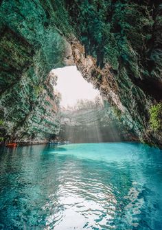 the inside of a cave with blue water and sunlight coming from it's entrance