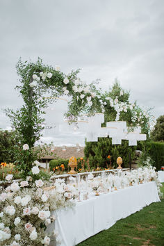 a long table with white flowers and greenery is set up for an outdoor wedding