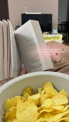 a white bowl filled with chips next to an open book