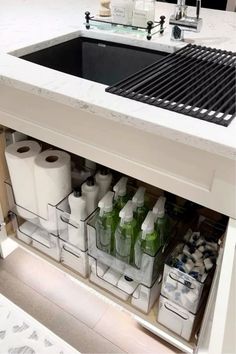 a kitchen sink filled with lots of bottles and paper towels next to a counter top