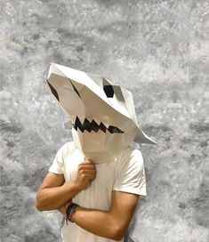 a man with a paper bag on his head is posing for the camera while wearing an origami shark mask