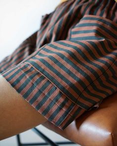 a person sitting in a chair with their legs crossed and wearing shorts that have stripes on them