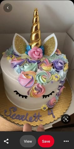 there is a cake decorated with flowers and a unicorn's head on top, in a box