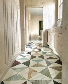 a long hallway with white and green tiles on the floor