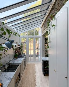 an indoor kitchen with white cabinets and marble counter tops, plants growing on the wall