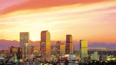 the city skyline is lit up at night with mountains in the backgrouund