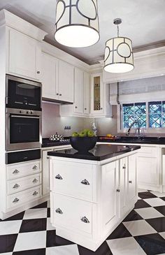 a kitchen with black and white checkered flooring, two pendant lights over the island