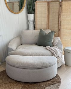 a living room with a round couch and mirror