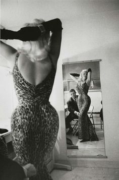 a woman in a leopard print dress standing next to a mirror