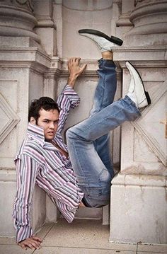 a man leaning up against a wall with his feet on the ground and one leg in the air