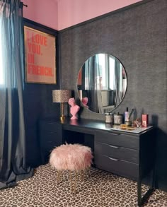 a pink and black bedroom with leopard print flooring, a cheetah rug and a vanity