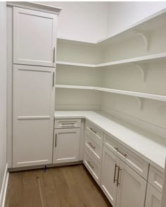 an empty kitchen with white cupboards and wood flooring on the side walk - in closet