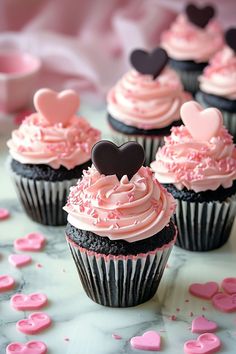 cupcakes with pink frosting and black hearts on the top are ready to be eaten