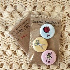 three button badges are sitting on top of a piece of fabric, with the words sweetie pie dress printed on them