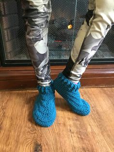 someone wearing blue slippers standing in front of a fireplace