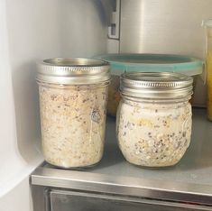 two jars filled with food sitting on top of a microwave oven next to each other