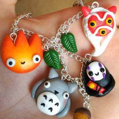 a hand holding four different animal charms on it's fingers, including an owl, panda, and other animals