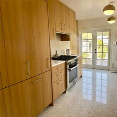 an empty kitchen with wooden cabinets and stainless steel stove top oven in front of sliding glass doors