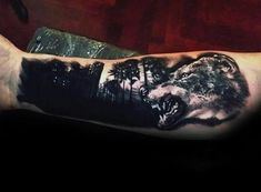 a man's arm with a wolf tattoo on it and trees in the background