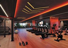 there are many exercise machines in the gym with orange lighting on the ceiling and wood flooring