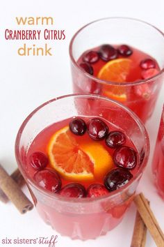 two glasses filled with liquid and garnished with orange slices, cranberries, and cherries