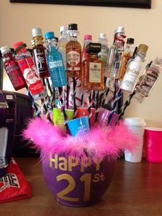 a purple vase filled with lots of liquor bottles and feathers on top of a wooden table