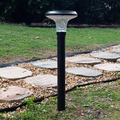 a black and white solar powered light in the grass near some stepping stone walkways