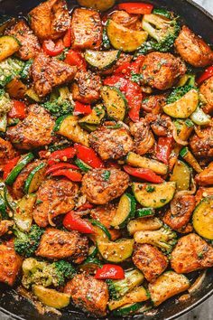 a skillet filled with chicken, peppers and broccoli on top of a table