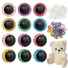 a white teddy bear sitting next to many different colored jeweled buttons and an assortment of other colorful sequins