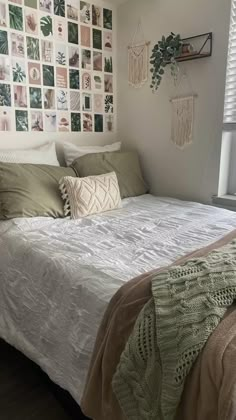 a white bed sitting under a window next to a wall with pictures on the walls