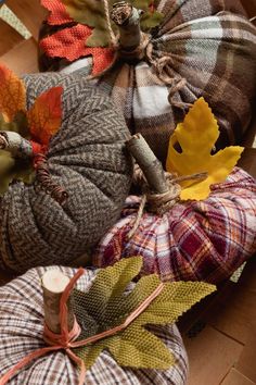 several plaid pumpkins are arranged on the floor with autumn leaves and twine spools