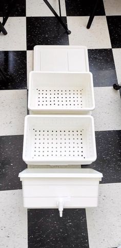 three white baskets sitting on top of a black and white checkered floor next to each other