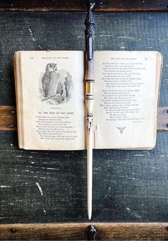 an open book with a pen sticking out of it's cover on a wooden table