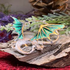 This unique piece was created with solid sterling silver and green enamel detailing to create a dramatic and magical dragon brooch that will be a special gift. The beautiful enamel work on the wings are done in an ombre style that gradually goes from a deep emerald green to a pale jade green to give the wings a realistic look. The intricate detailing on the dragon's body and face are magical! This is a must-see piece that is a work of art. No two pieces are exactly alike. A great way to show you Magical Dragon, Dragon Brooch, Deep Emerald Green, Dragons Gift, Ombre Fashion, Crystal Design, The Wings, Green Enamel, Jade Green