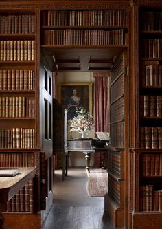 an old library with lots of bookshelves and a desk in the middle,