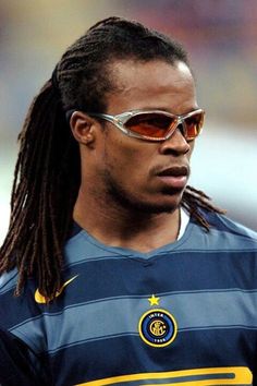 a man with dreadlocks wearing sunglasses on his head and looking off to the side