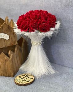 a bouquet of red roses in a vase next to a wooden box with a sign on it